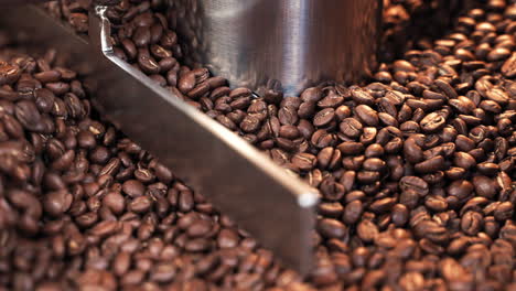 granos de café tostados de primer plano girando y mezclando en tostador de tambor en cámara lenta