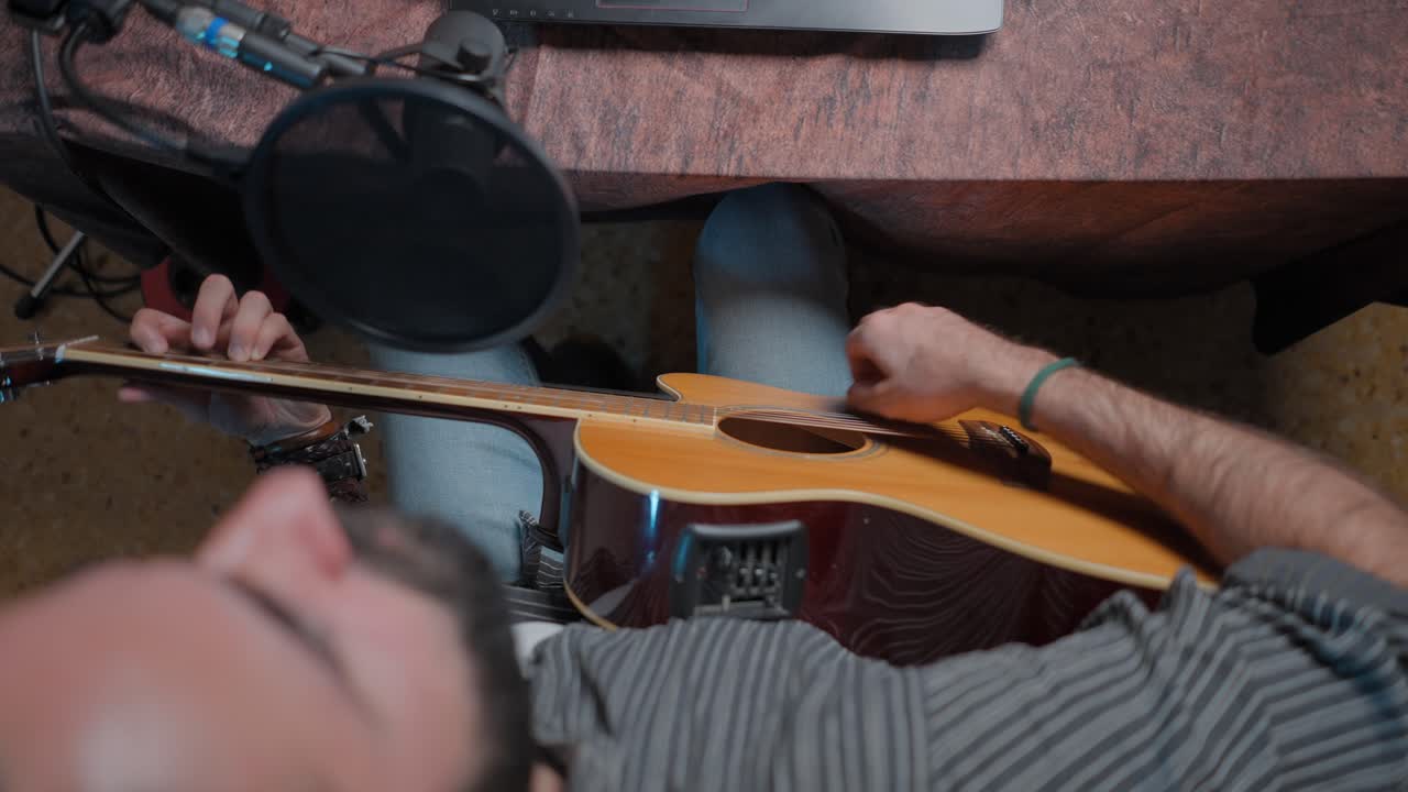 Person Playing Acoustic Guitar in Home Studio