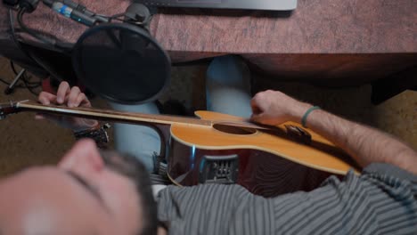 person playing acoustic guitar in home studio