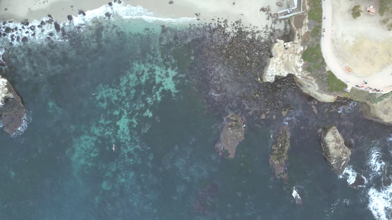 Peaceful 4K drone shot rising above the Pacific Ocean at La Jolla Shores with a slow cinematic spin during a calm summer evening. Perfect for travel, tourism, or cinematic projects