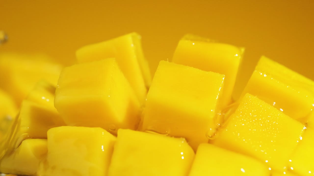 toma en cámara lenta de verter agua salpicando rebanadas de cubo de mango, toma macro extrema
