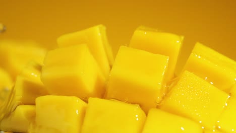 Slow-Motion-Shot-of-pouring-water-Splashing-through-Mango-Cube-Slices,-Extreme-macro-shot