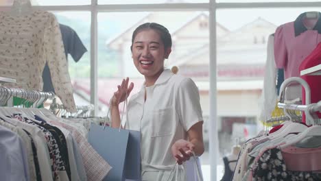 cheerful young asian woman with the shopping bags dancing celebrating be able to buying clothes while shopping at the boutique