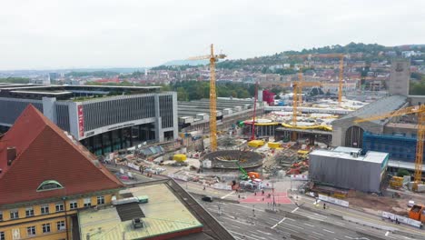 Antena-Del-Sitio-De-Construcción-De-La-Estación-De-Tren-Principal-Stuttgart-S21-Con-Grúas-Y-Trabajadores-De-La-Construcción-Descendiendo-Sobre-Stuttgart,-Alemania