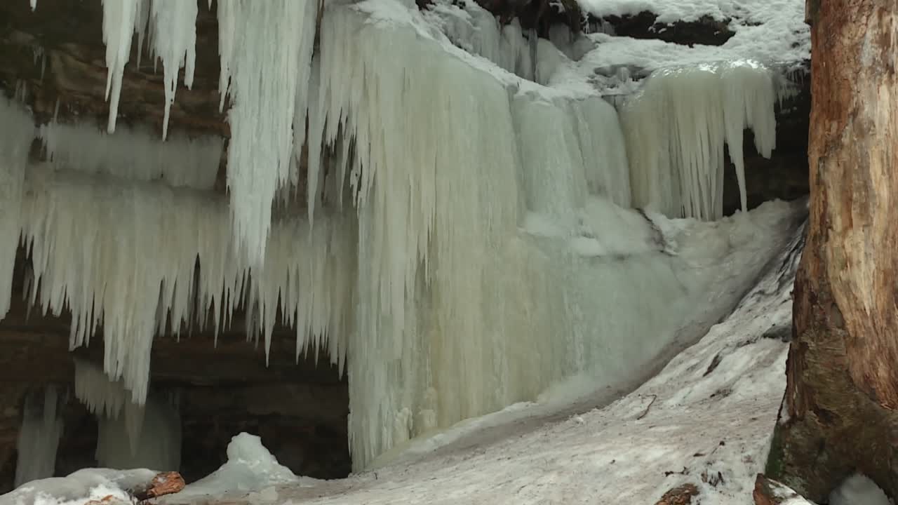 Thick icicles and ice sheets hang from rocky overhang at Eben Ice Caves, USA