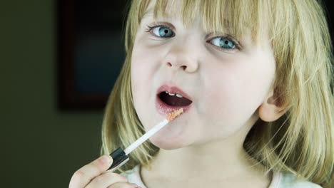 little girl applying lipstick