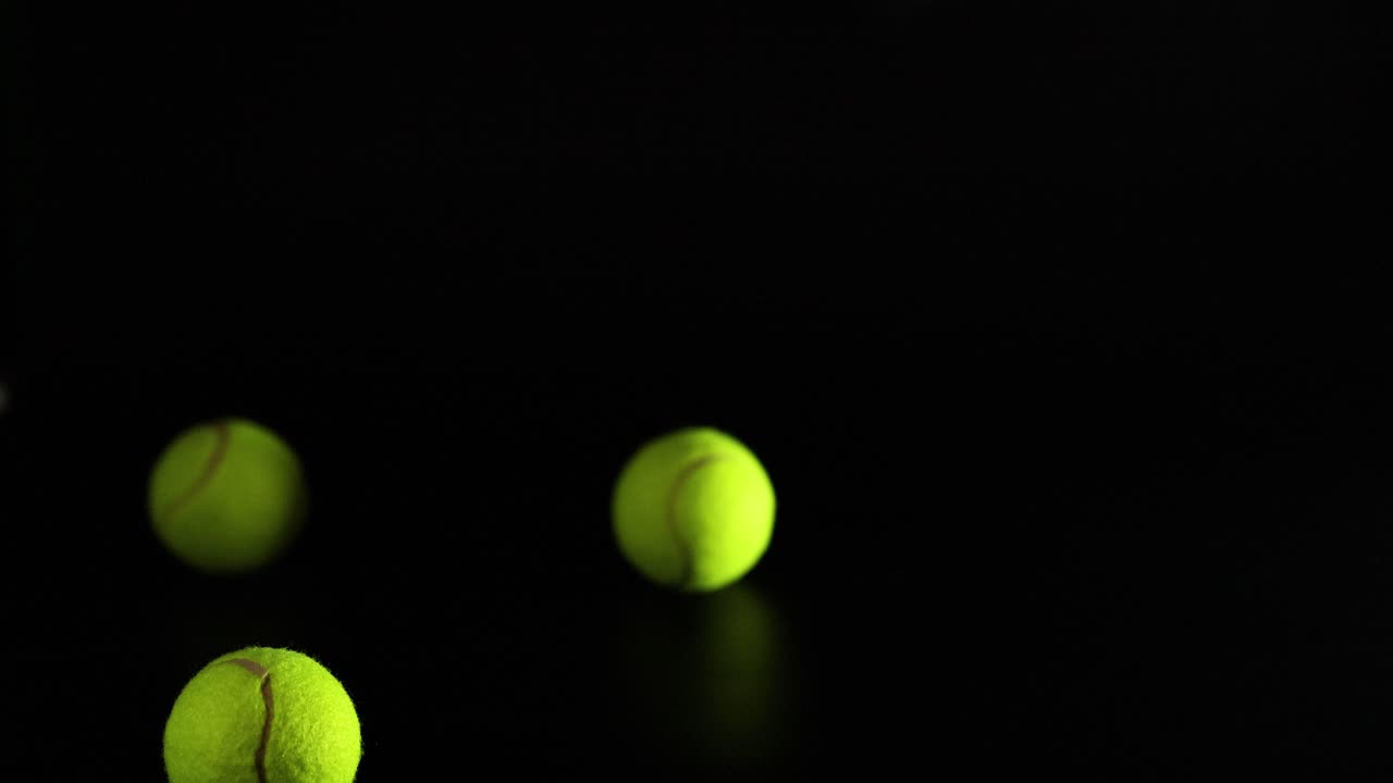 다중 테니스 공이 어두운 배경에서 뛰고 있습니다.