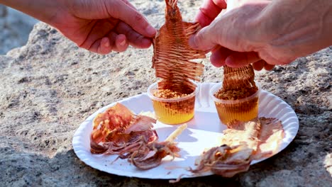 hands sharing dried squid with dipping sauce