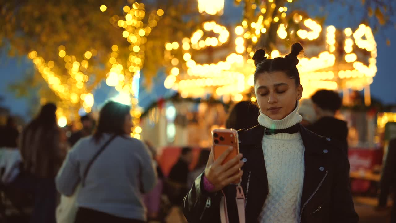 Mujer usando el móvil en una feria nocturna