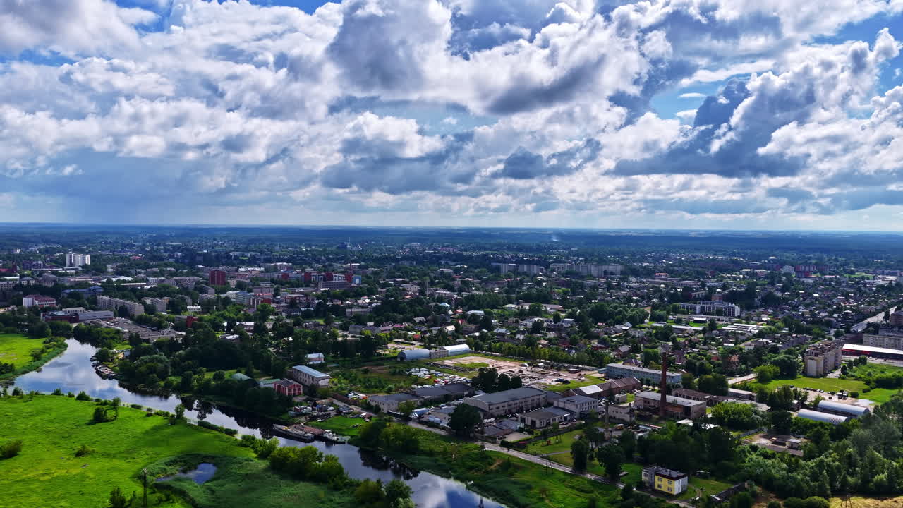 Profile view of a cityscape surrounded with greenery on a cloudy day. Aerial shot