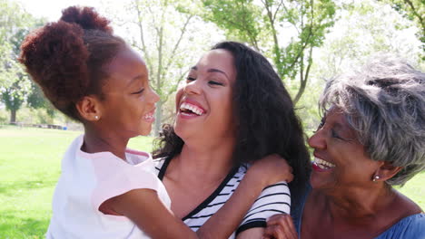 portrait of grandmother with adult daughter and granddaughter relaxing in park
