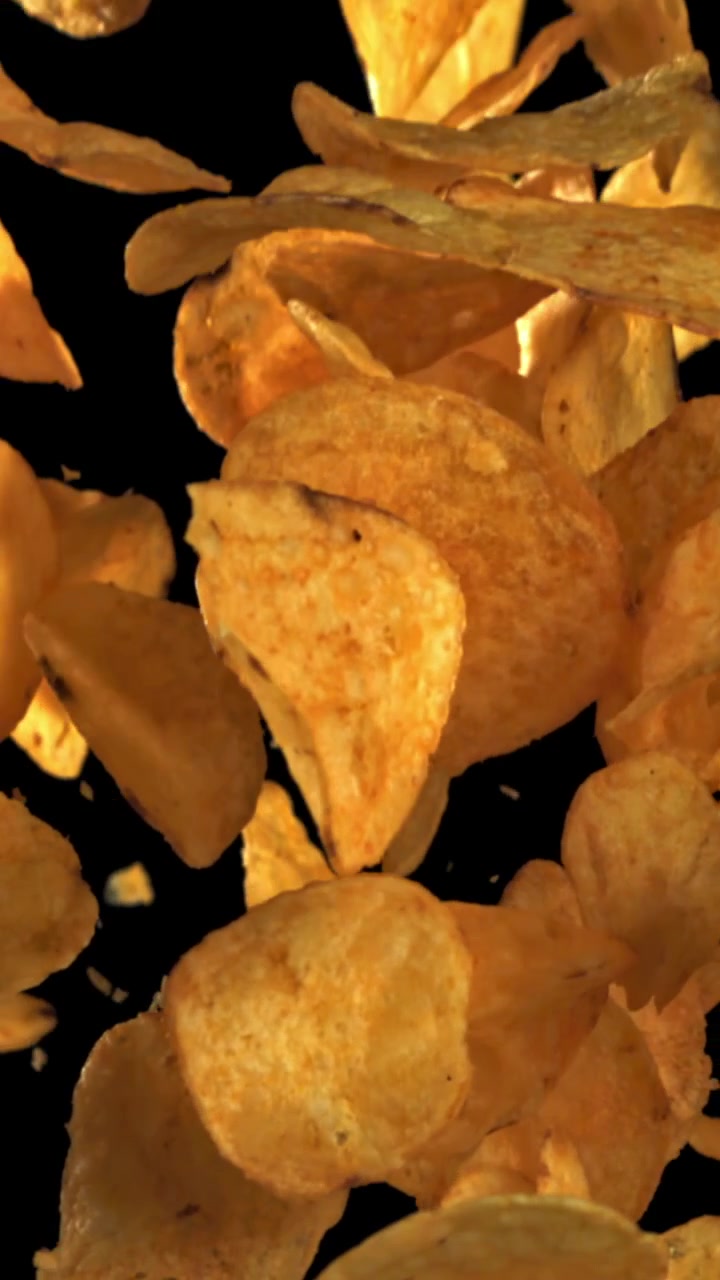 Golden Crispy Potato Chips Falling in Slow Motion on Black Background