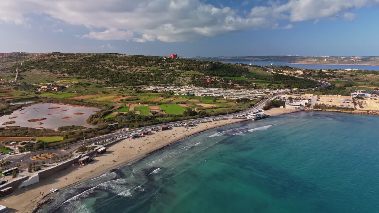 Vista orbitale da drone di Mellieħa, Malta, che mette in risalto la meravigliosa Ghadira Bay, la Torre Rossa, le spiagge sabbiose, la riserva naturale con lago e i rigogliosi paesaggi mediterranei in una soleggiata giornata invernale