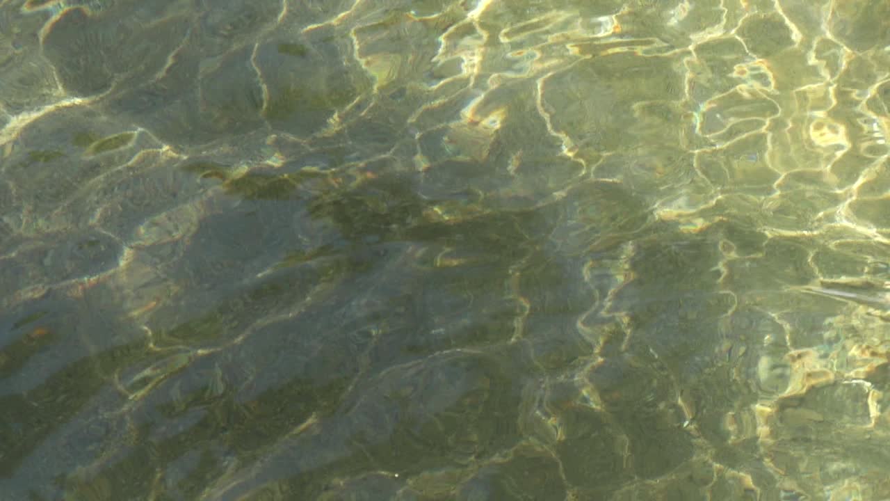 Water surface, ripples and sun shining through, slow motion 120p slowed to 24p