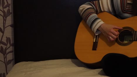 pan of a girl practicing guitar on the bed