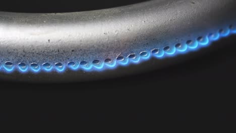 quemador de gas en el horno de primer plano en un fondo negro. video crudo macro 4k.