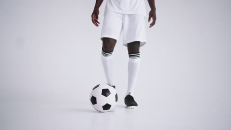 soccer player is dribbling ball in studio and posing for camera portrait of footballer