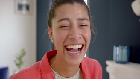 Portrait-of-happy-biracial-teenage-girl-standing-at-home-laughing,-slow-motion