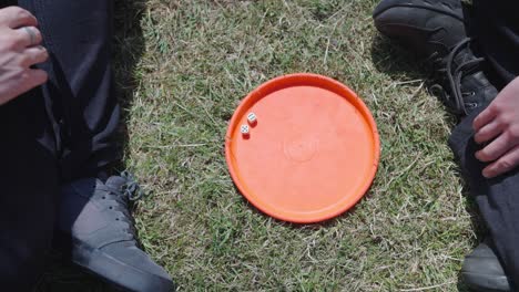 two people in black sitting on grass and playing with dice, slow motion