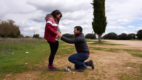 pregnant couple walking in the countryside showing a pair of baby boots