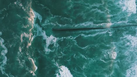 Aerial-cenital-plane-shot-of-waves-crashing-at-the-wall-of-Tijuana-at-sunset