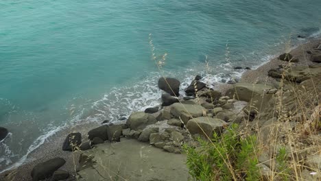 Green-coast-with-beautiful-isolated-quiet-beach-and-carved-cliffs-washed-by-sea-waves-in-Mediterranean