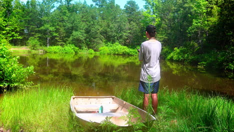 Boy-fishing-on-the-shore-of-a-scenic-pond-on-a-sunny-afternoon