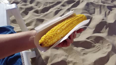 holding sweet corn on the beach