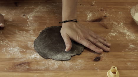 Hands-press-Christmas-cookie-cutter-into-gingerbread-dough,-high-angle