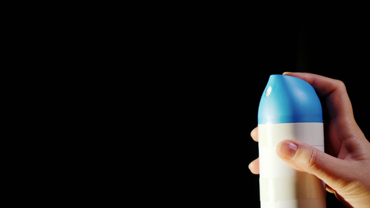 un primer plano de una lata de aerosol. pulverización de pulverización sobre un fondo negro