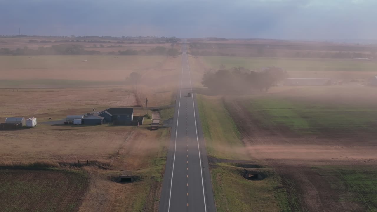 Dusty Oklahoma highway with rural landscape and cars passing by