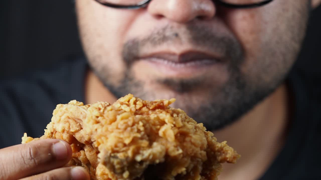 Person Eating a Piece of Fried Chicken