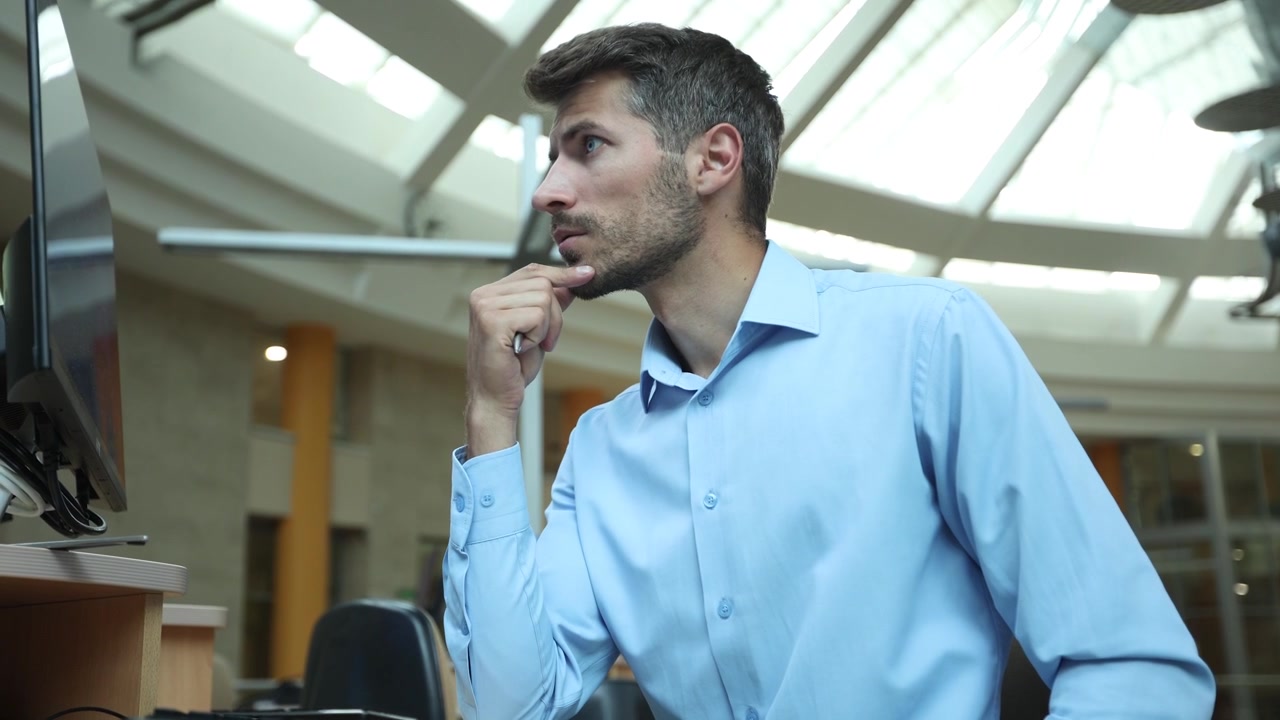 Uomo d'affari concentrato che scrive e digita al computer in un ufficio moderno
