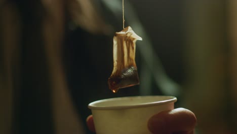 man pulls tea bag from cup