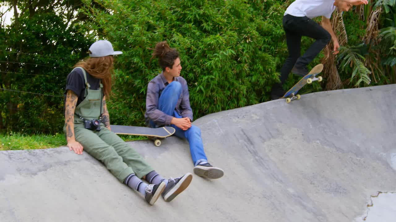 스케이트보드 파크 4k의 램프에서 스케이트보드를 연습하는 젊은 백인 남자의 측면 뷰