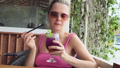 mujer disfrutando de una bebida púrpura al aire libre