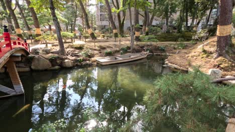 person walking over a red bridge in a tranquil garden