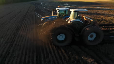 agricultural tractor cultivating a field at sunset