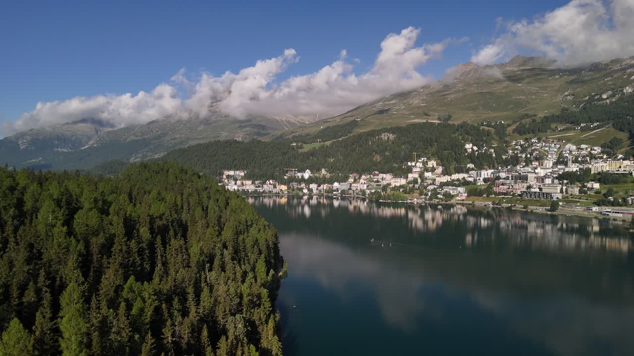 Aerial view of Lake St. Moritzersee in Graubünden, Switzerland, with majestic mountains towering above the residential houses, blending natural beauty with alpine living in a serene setting.