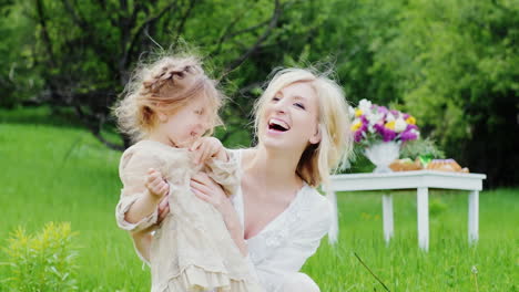 cute little girl in a stylish light dress plays fun with her mom in the courtyard of the house