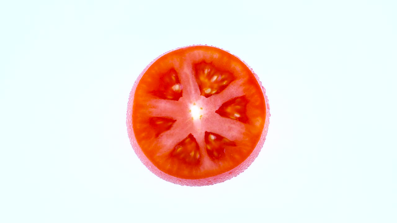 색 바탕에 고립 된 회전 테이블에서 회전하는 물방울과 함께 반 은 토마토의 절단.