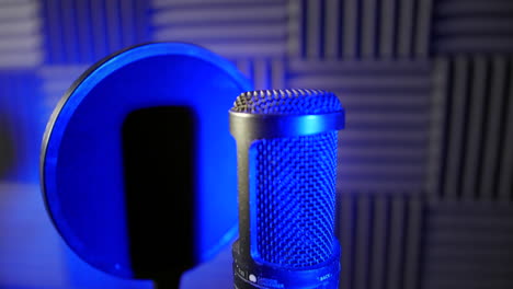 dolly shot of a condenser capacitor microphone in a voice over podcast vocal booth in a recording studio