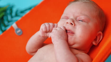 lovely caucasian blue-eyed blond infant. little baby moving hands and making faces. close up.
