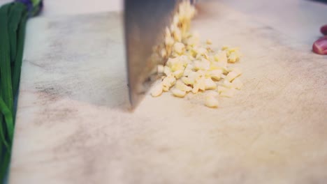 a chef slices garlic on chopping board close up