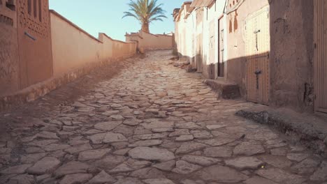 cinematic reveal shot of old and occupied houses with a rocky and uneven road in a poor and unwealthy suburb in morocco in north africa