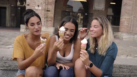 felices y vivas jóvenes estudiantes comiendo conos de helado riendo y bromeando en el caluroso sol de verano
