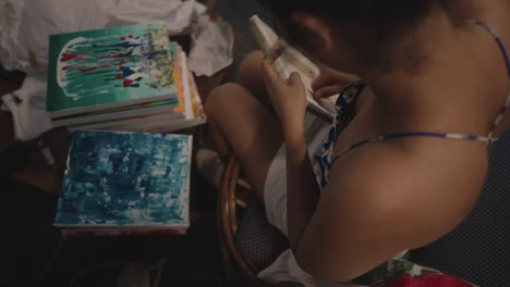 an asian young women working on fixing painting frames with screws , sitting on chair to sell it