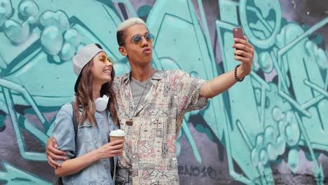 pareja divertida hipster con ropa elegante haciendo un selfie con un smartphone en la calle