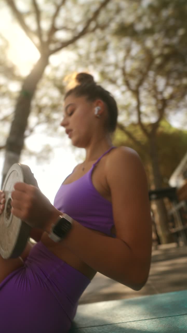 A woman performing an outdoor core workout with a weight plate