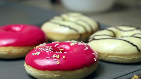 Close-up-of-a-woman's-hand-decorating-a-donuts-while-baking-them,-dessert-and-bakery-pastry-concept